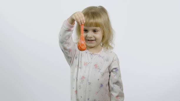 istock Kid playing with hand made toy slime. Child having fun making orange slime 1196510325