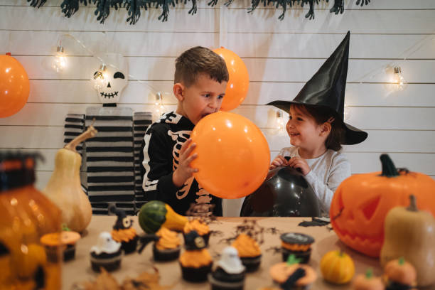 istock Kids blowing balloons for Halloween decoration 1196511584