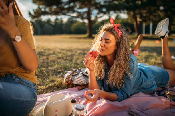 молодая женщина наслаждаясь кекс на пикник - glasses grass women lying on front стоковые фото и изображения