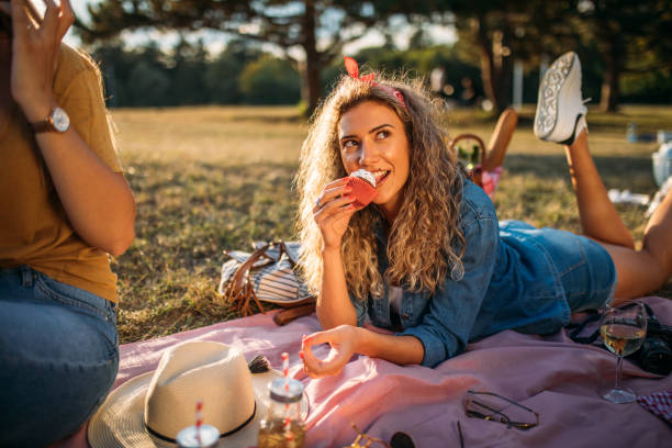 молодая женщина ест кекс - glasses grass women lying on front стоковые фото и изображения