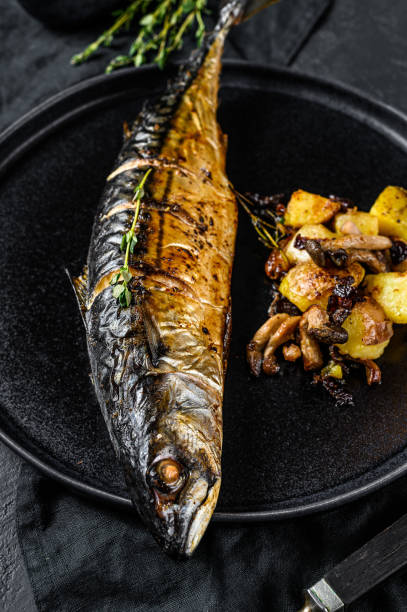 istock smoked mackerel with fried potatoes and mushrooms. Black background. Top view 1196514068
