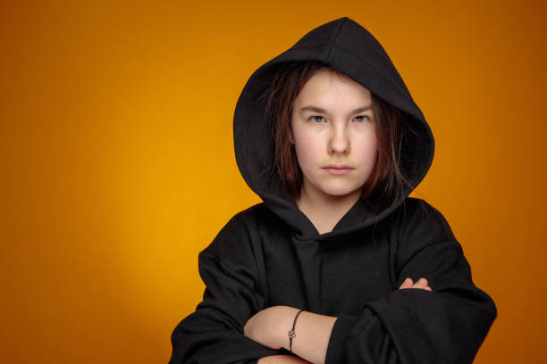 angry teenage girl in black hood with confident eyesight looking straight at camera stock photo
