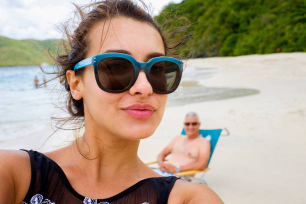 Beach Selfie Beautiful young multicultural woman taking a selfie at the beach with her father photobombing in the background. photo bomb stock pictures, royalty-free photos & images