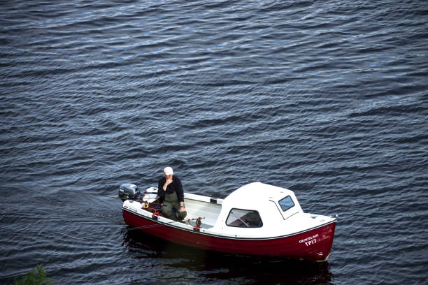 Fisherman in a boat at Loch Ness, Scotland. Drumnadrochit, Inverness, Scotland, UK - August 1, 2016: Angler in motorboat fishing at Loch Ness. drumnadrochit stock pictures, royalty-free photos & images