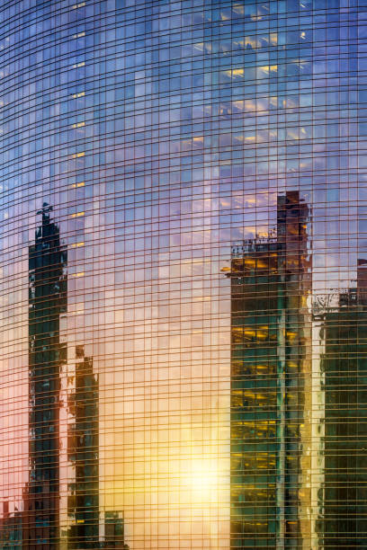 Office buildings at sunset. The glass facade of a skyscraper strongly reflects the setting sun and the sky.