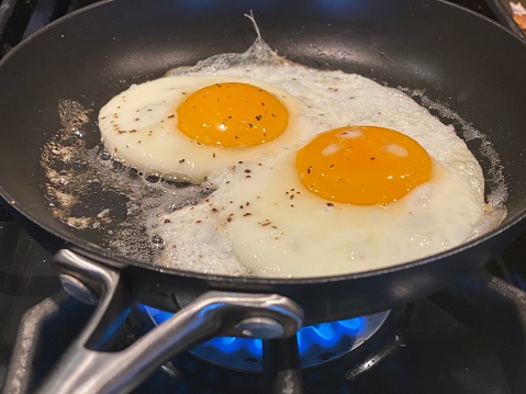 Sunny side up eggs with pepper cooking in a pan.