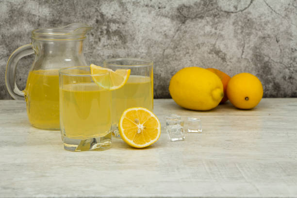 istock Fresh lemon juice with ice with fresh lemons on a gray background. Lemonade with fresh lemons on a gray background. Fresh juice lemonade. 1196529510