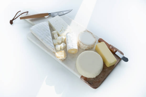 Farm cheeses for the cold autumn and winter season. Young Camembert, Maasdam, Tomino with grapes and almonds. Winter food concept. Selective focus