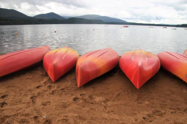 canoes on the banks of loch morlich. scotland, uk. - loch rowboat lake landscape imagens e fotografias de stock