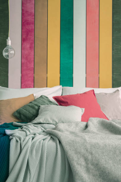 closeup of king size bed with green, yellow, red and grey pillows - accent wall imagens e fotografias de stock