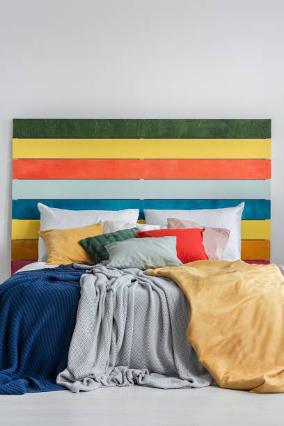 istock Colorful bed with pillows, blankets and bedhead with rainbow colored wood 1196542594