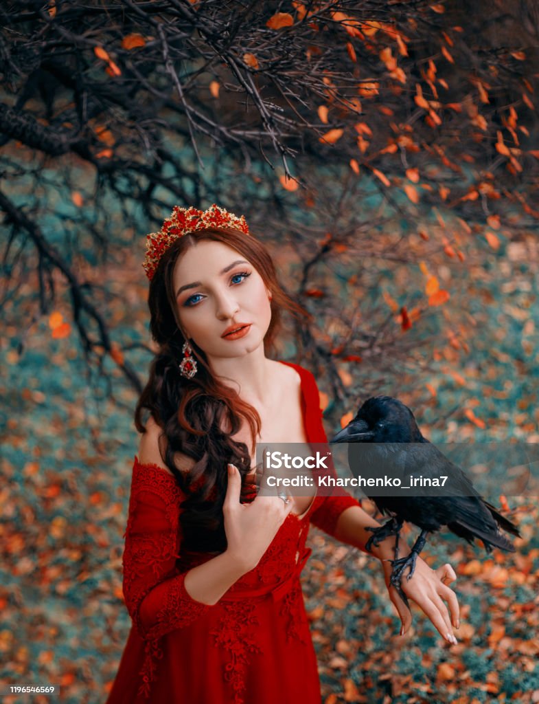 Mujer De Retrato Con Cuervo A Mano Reina En Vestido De Moda Rojo Cuello Seductor Profundo Pecho Abierto Corona Dorada Piedras Rojas Telón De Fondo De La Naturaleza Otoñal Árbol Con Hojas Mujer De Retrato Con Cuervo A Mano Reina En Vestido De Moda Rojo Cuello Seductor Profundo Pecho Abierto Corona Dorada Piedras Rojas Telón De Fondo De La Naturaleza Otoñal Árbol Con Hojas