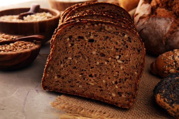 istock Assortment of baked bread and bread rolls and cutted bread on table background 1196549983