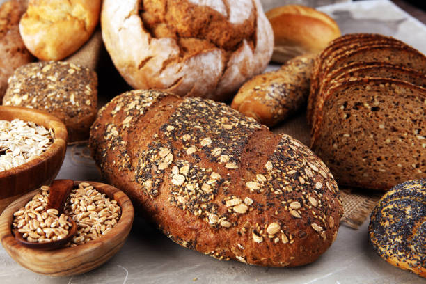 istock Assortment of baked bread and bread rolls and cutted bread on table background 1196550006