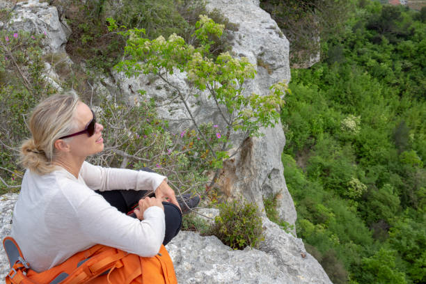 istock Hiker sits on edge of cliff above a forest 1196550014