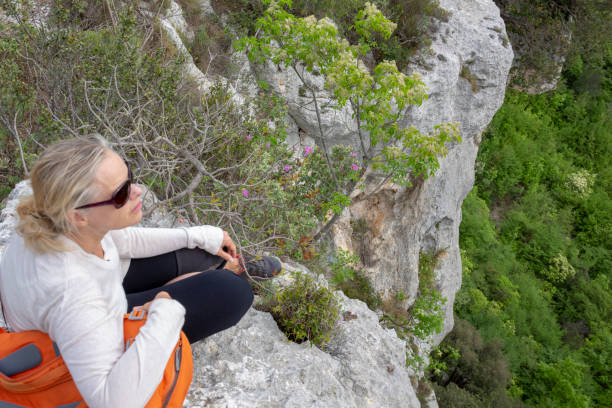 istock Hiker sits on edge of cliff above a forest 1196550019