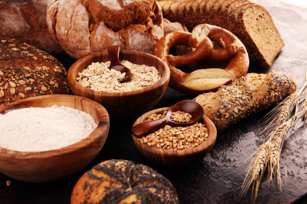 istock Assortment of baked bread and bread rolls and cutted bread on table background 1196550319
