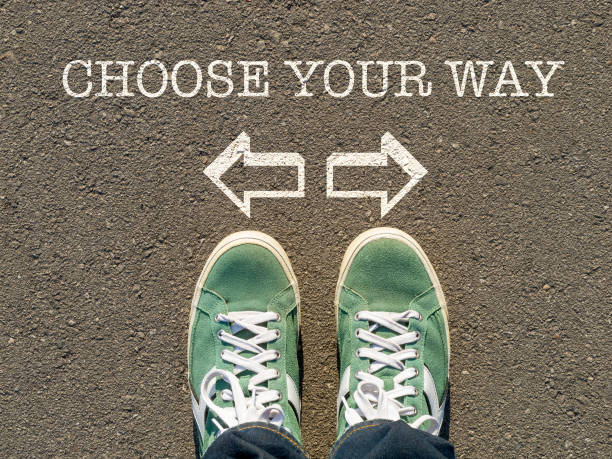 the concept of free choice, direction of movement photo on top of the sneakers and the inscription choose your way on the asphalt, the concept of free choice, direction of movement, the philosophical question of life job retraining stock pictures, royalty-free photos & images