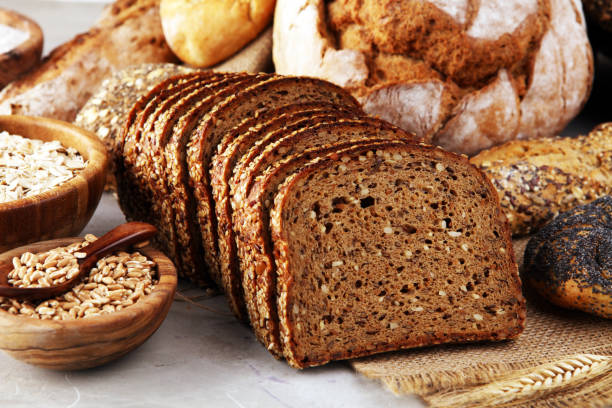 istock Assortment of baked bread and bread rolls and cutted bread on table background 1196551547