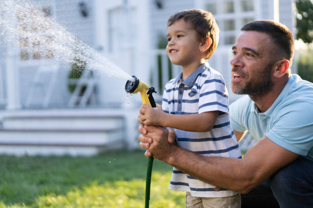 istock Father splashing water and having fun with son on back yard 1196552348