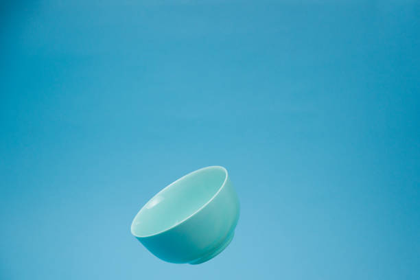 istock A blue ceramic mattle deep bowl for breakfast flying on blue background. 1196553198
