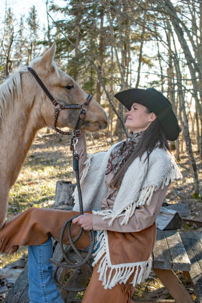 istock Cowgirl next to a blond colored colt 1196553250
