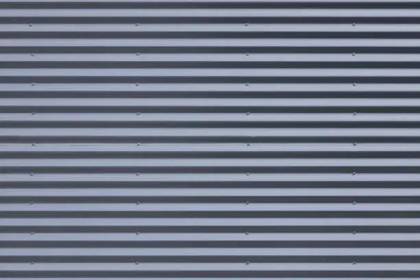 Close-up of grey metal ribbed wall in daylight