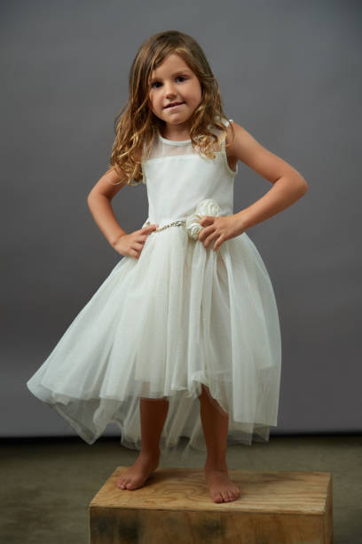 istock Girl in white dress with hands on hips 1196573219