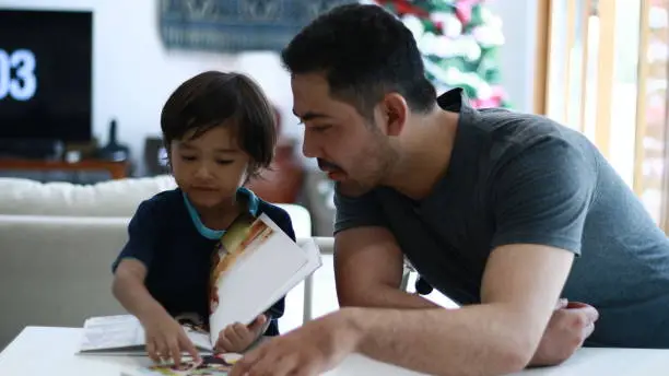 Indonesian kid read books accompanied by father.