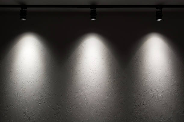 White wall with track light. Spotlight beams on the wall. Dark background White wall with track light. Spotlight beams on the wall. Dark background recessed light stock pictures, royalty-free photos & images