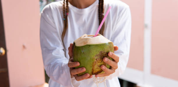 istock drinking coconut in female hands close up. 1196582609