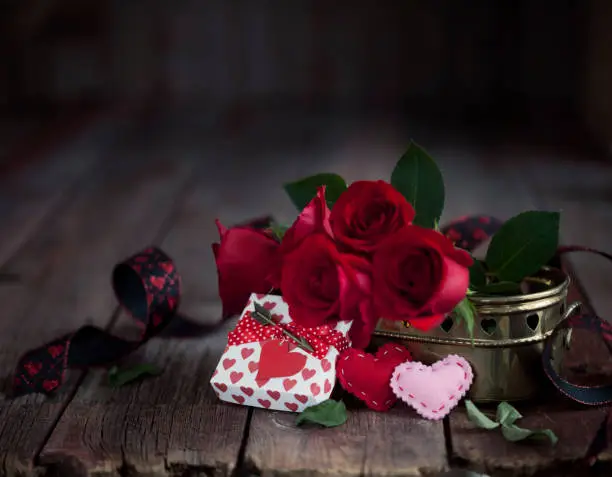 Photo of Valentine's Day Gift with Red Roses on a Dark Wood Background