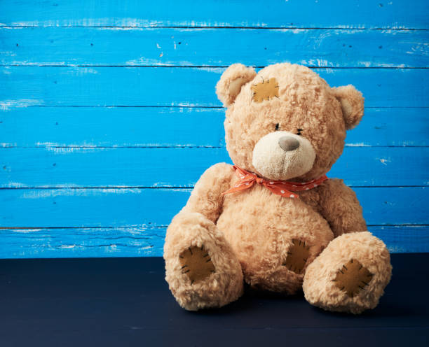 istock big beige teddy bear sitting on a blue wooden background 1196592652