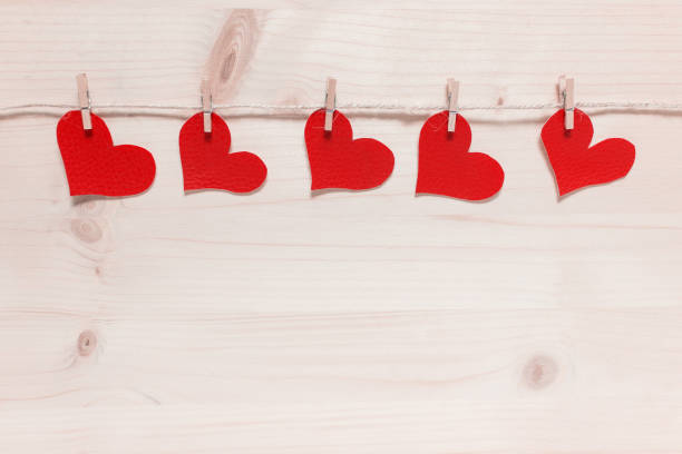 istock Valentines hearts pinned to packthread on wooden backgound 1196593401