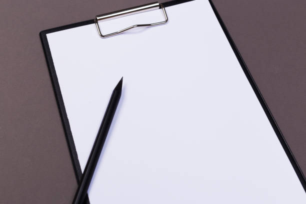 istock Clipboard with white sheet and pen on a colored background. View from above. space for text 1196596920
