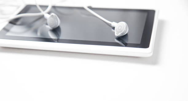istock Tablet with a earphones on white desk. 1196603445