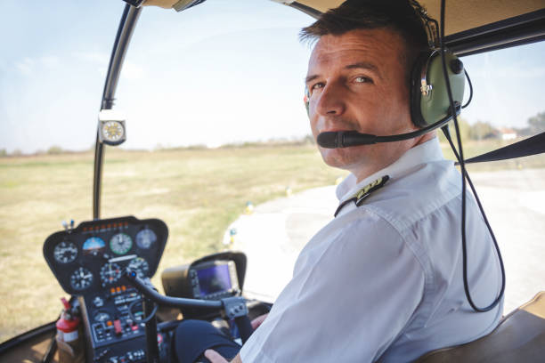 istock Pilot with headphones on in cockpit looking at camera over shoulder 1196604497