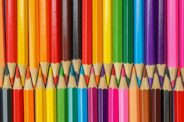 Close up row of interlocking colored pencils in a rainbow of colors