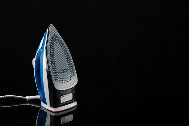istock The iron on a black mirror background with copy space 1196618181
