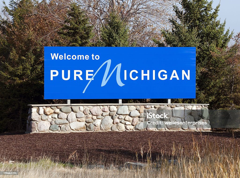 Blue welcome to pure michigan sign on a stone wall A welcome sign at the Michigan state line. Michigan Stock Photo