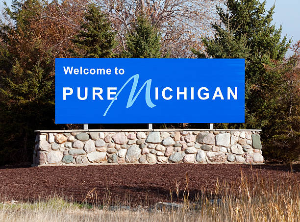 Blue welcome to pure michigan sign on a stone wall A welcome sign at the Michigan state line. flint michigan stock pictures, royalty-free photos & images