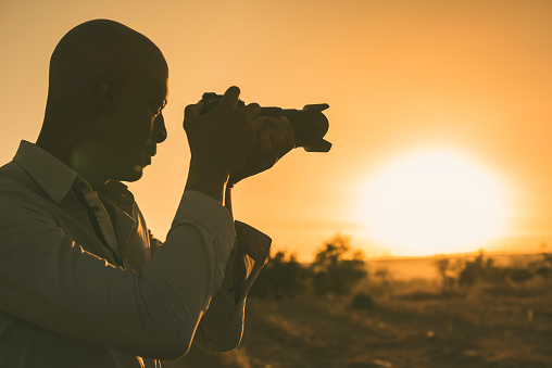 Black photographer taking pictures at sunset. Image with copy space.