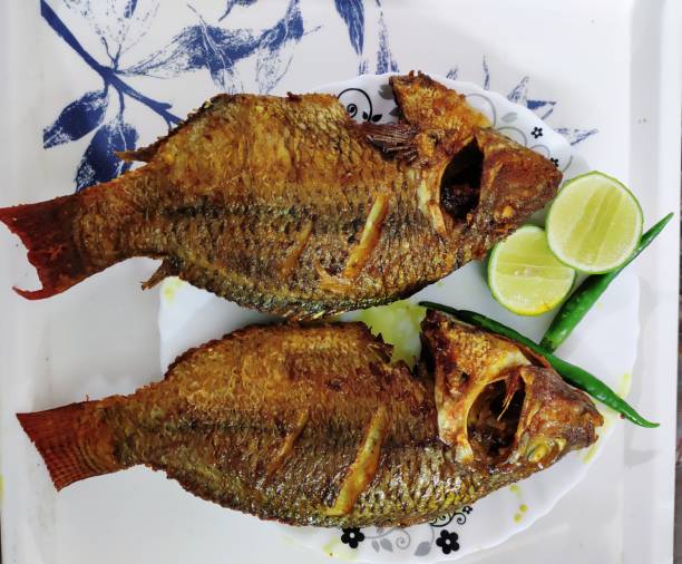 istock Two deep fried fish with lemon and green chilies 1196629988