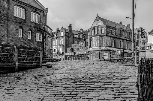 Scarborough, UK.  November 29, 2019.  Looking up a cobbled slipway in Scarborough towards some shops and an amusement arcade.  A weathered mooring post is in the foreground.