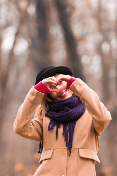 joven mujer al aire libre haciendo corazón - símbolo de forma para el amor y el romance. - heart shape loneliness women praying fotografías e imágenes de stock