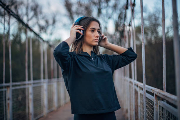 istock Young woman with headphone standing on the bridge 1196640981
