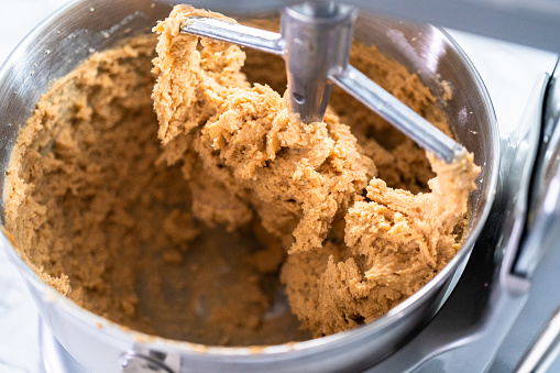 Mixing ingredients in standing kitchen mixer to bake peanut butter cookies.