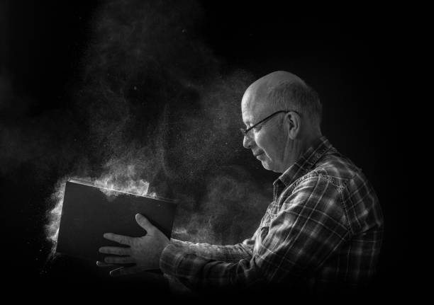 senior man with old dusty book - portrait black and white senior men wisdom imagens e fotografias de stock
