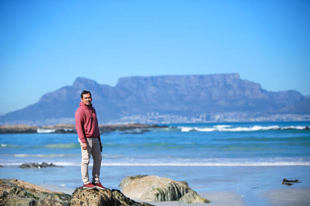 istock an asian man standing on the beach with table mountain behind 1196655928
