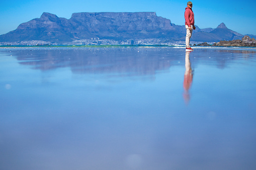 South Africa, Cape Town, man standing on the beach with table mountain behind